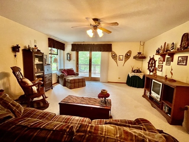 living room with a textured ceiling, light colored carpet, and ceiling fan