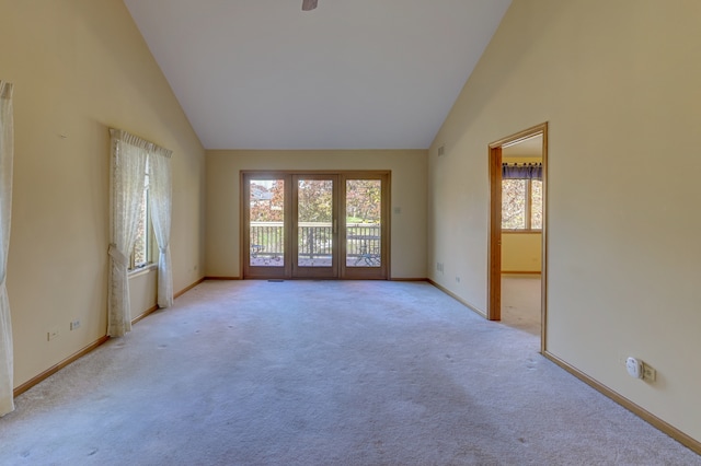 carpeted spare room featuring high vaulted ceiling