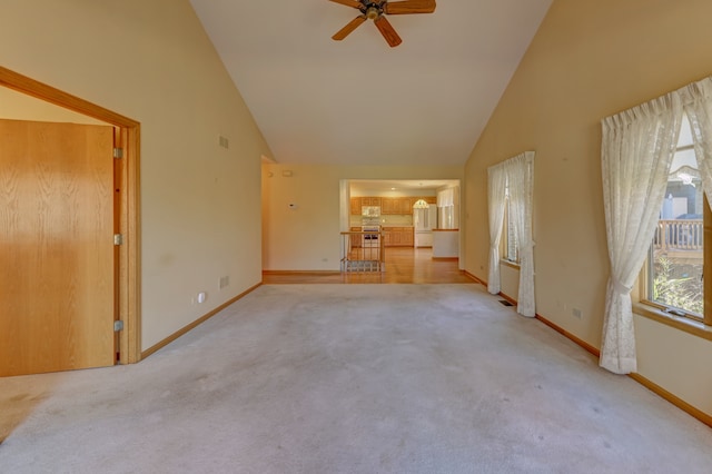 unfurnished living room with light carpet, high vaulted ceiling, and ceiling fan