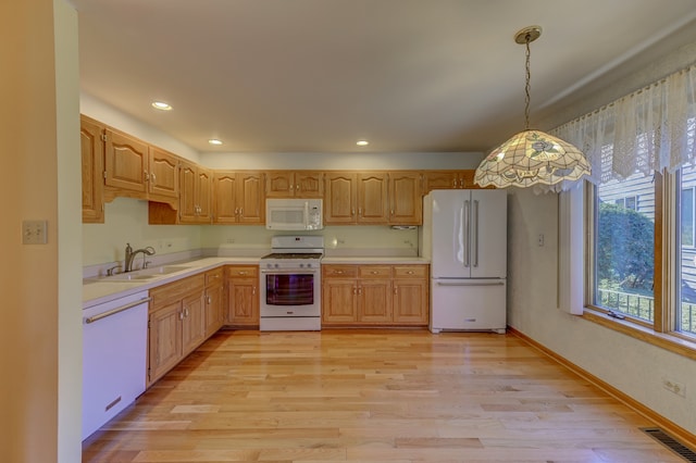 kitchen with sink, hanging light fixtures, light wood-type flooring, and white appliances