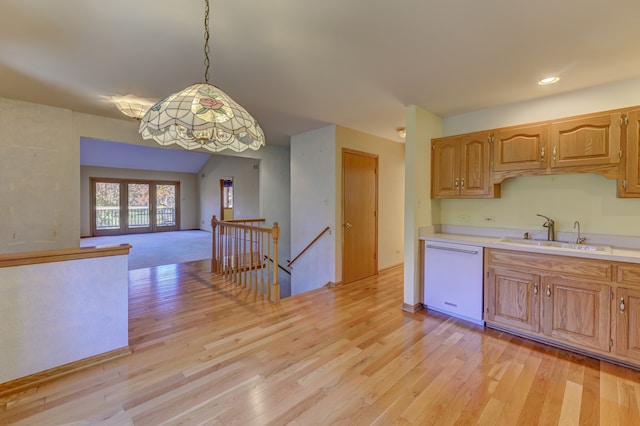 kitchen with sink, dishwasher, hanging light fixtures, and light wood-type flooring