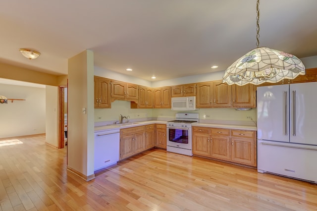 kitchen with sink, light hardwood / wood-style flooring, hanging light fixtures, and white appliances