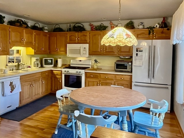 kitchen with hardwood / wood-style floors, decorative light fixtures, sink, and white appliances