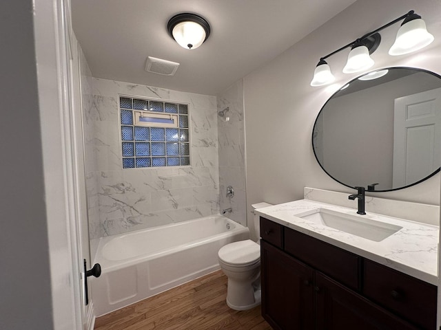 full bathroom featuring tiled shower / bath combo, wood-type flooring, vanity, and toilet