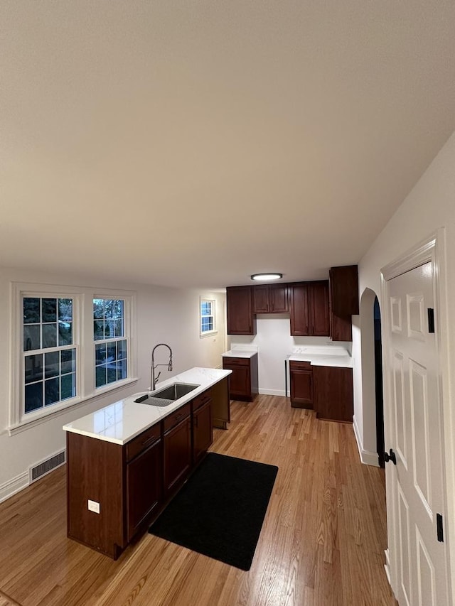 kitchen featuring dark brown cabinets, sink, a center island with sink, and light hardwood / wood-style floors