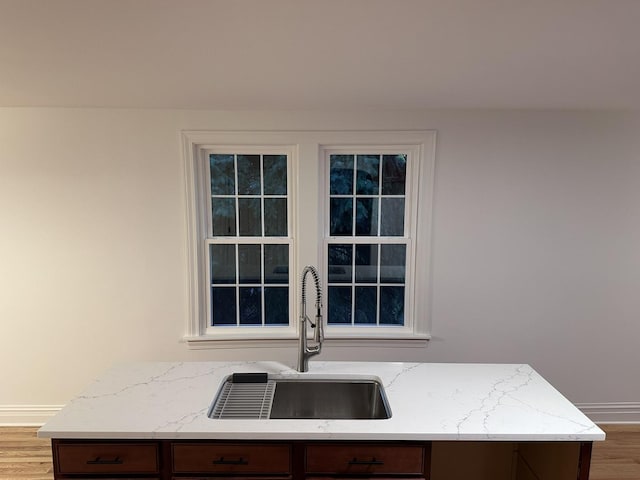 kitchen featuring light stone countertops, sink, and light hardwood / wood-style floors