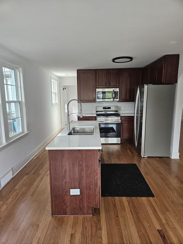 8646 S Nagle Ave, Burbank, IL 60459 - kitchen with stainless steel appliances, a sink, a center island with sink, light countertops, and dark wood-style floors