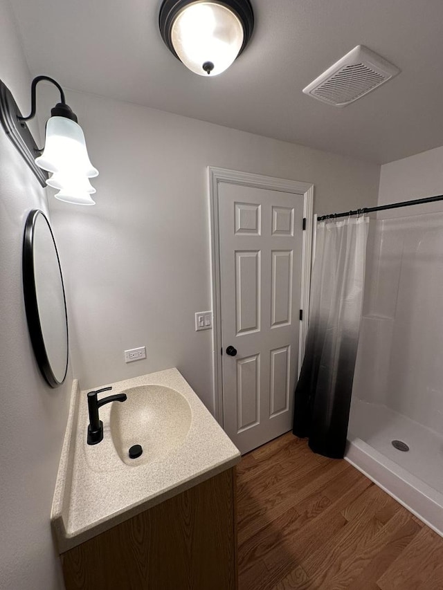 bathroom with walk in shower, vanity, and hardwood / wood-style floors