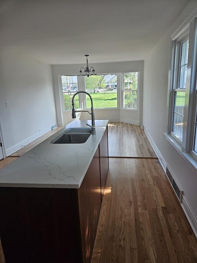 8646 S Nagle Ave, Burbank, IL 60459 - kitchen with hanging light fixtures, a sink, visible vents, dark wood-style flooring, and light stone counters