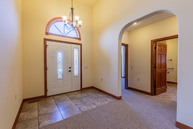 foyer entrance featuring a high ceiling, light colored carpet, and a notable chandelier