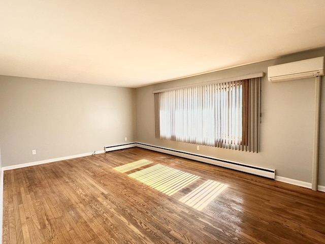 spare room with baseboard heating, a wall mounted AC, and hardwood / wood-style floors