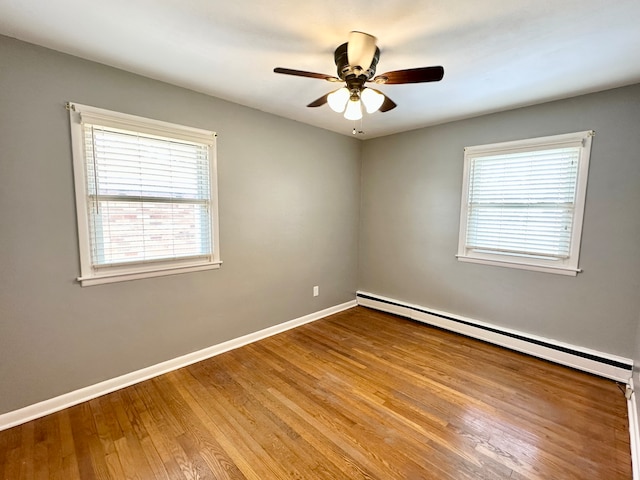 spare room with baseboard heating, ceiling fan, plenty of natural light, and light hardwood / wood-style flooring