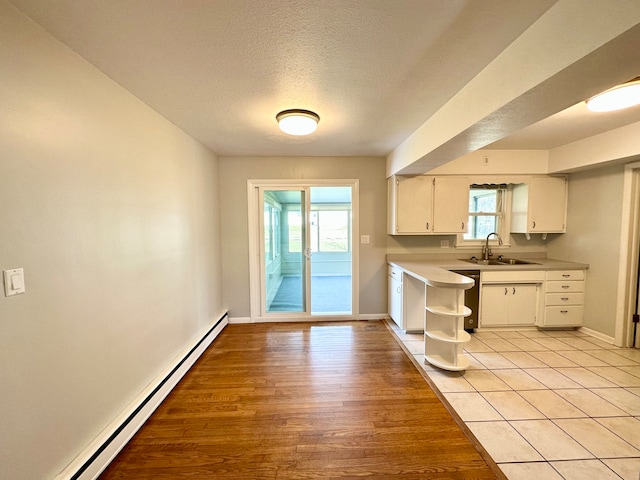 kitchen featuring white cabinetry, a baseboard radiator, sink, a textured ceiling, and light hardwood / wood-style flooring