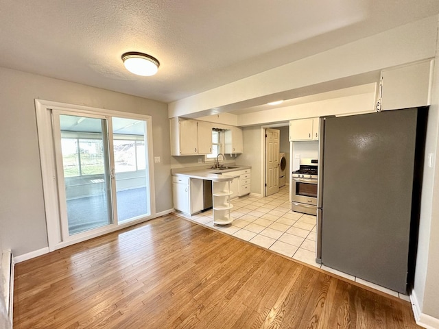 kitchen featuring sink, a textured ceiling, appliances with stainless steel finishes, light hardwood / wood-style floors, and white cabinets