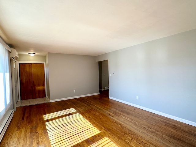 unfurnished room featuring dark hardwood / wood-style floors, a baseboard heating unit, and a wall unit AC