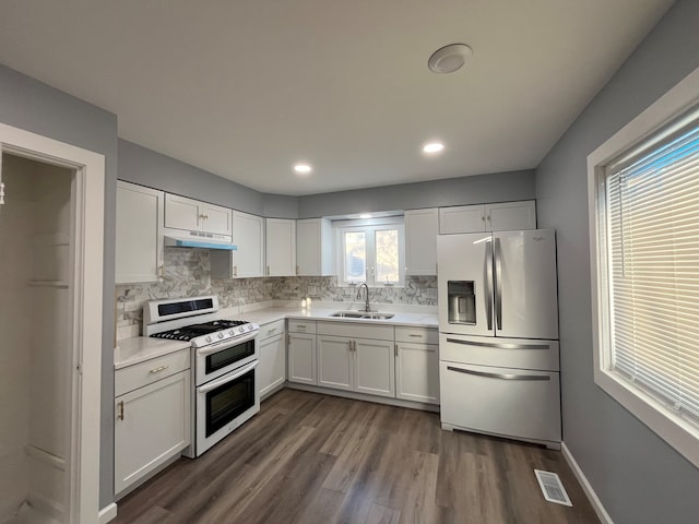 kitchen featuring double oven range, stainless steel fridge, sink, white cabinets, and dark wood-type flooring