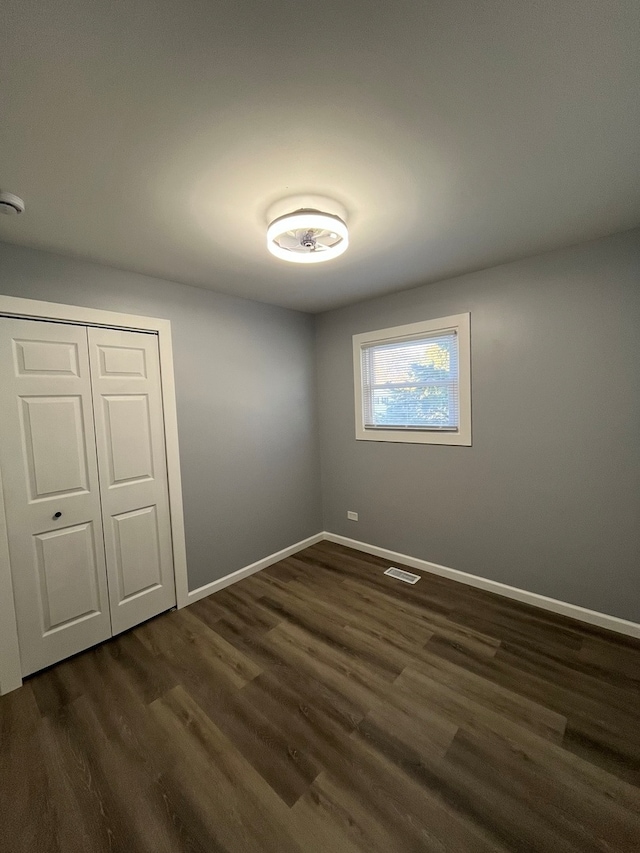 unfurnished bedroom with dark hardwood / wood-style floors and a closet