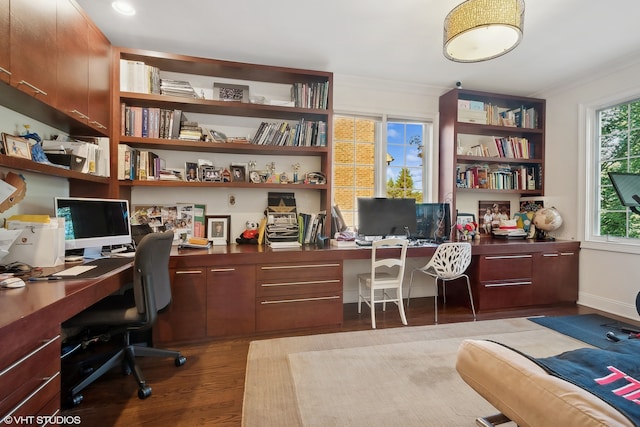 office featuring dark wood-type flooring, built in desk, and crown molding