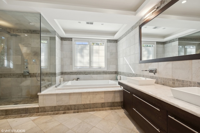 bathroom featuring tile patterned floors, independent shower and bath, a tray ceiling, vanity, and tile walls