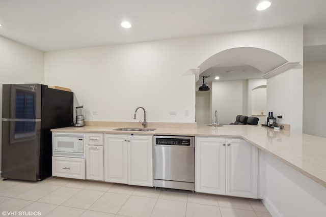 kitchen featuring appliances with stainless steel finishes, sink, light stone countertops, white cabinetry, and light tile patterned floors