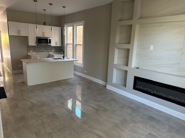 kitchen with white cabinets, tasteful backsplash, a kitchen island, pendant lighting, and sink