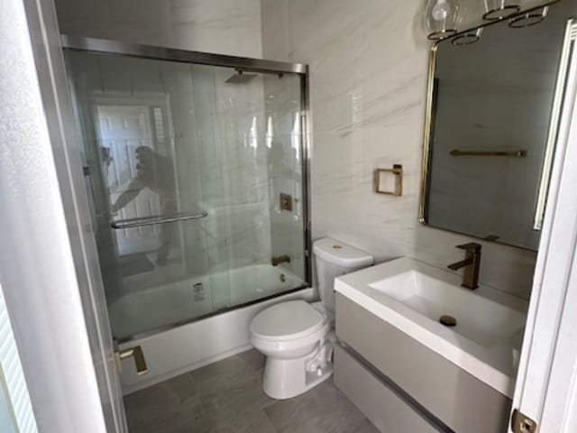 full bathroom featuring vanity, bath / shower combo with glass door, and toilet