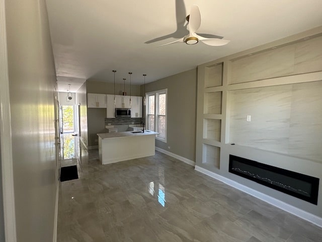 kitchen with white cabinets, tasteful backsplash, ceiling fan, pendant lighting, and sink