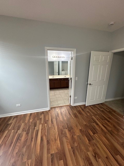 unfurnished bedroom with ensuite bathroom and light hardwood / wood-style flooring