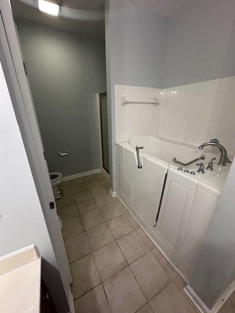 bathroom featuring toilet, tile patterned floors, and separate shower and tub