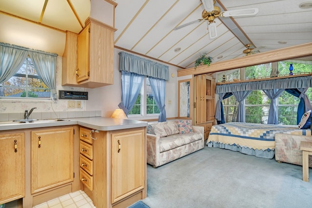 kitchen with sink, light brown cabinets, ceiling fan, light colored carpet, and vaulted ceiling