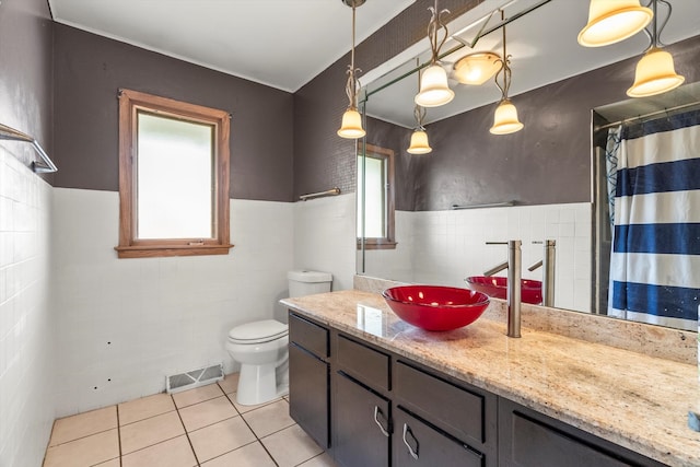 bathroom featuring toilet, vanity, tile patterned floors, and tile walls