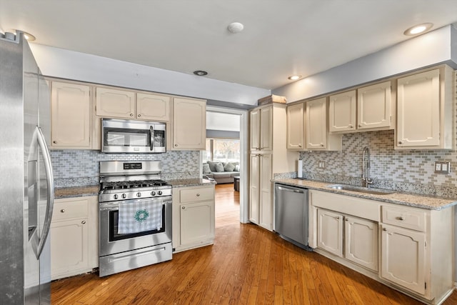 kitchen featuring sink, decorative backsplash, stainless steel appliances, and light wood-type flooring