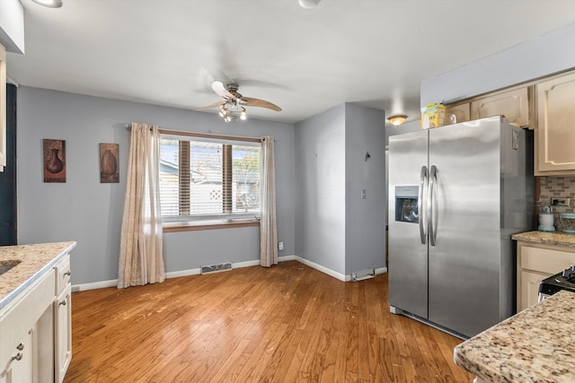 kitchen with decorative backsplash, ceiling fan, stainless steel fridge with ice dispenser, light stone countertops, and light hardwood / wood-style flooring