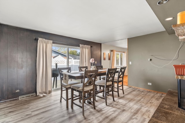 dining space featuring light hardwood / wood-style flooring and wood walls