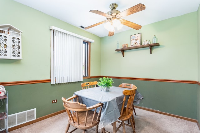 carpeted dining area with ceiling fan