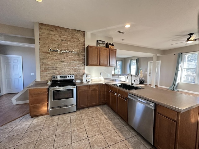 kitchen featuring kitchen peninsula, a wealth of natural light, sink, and appliances with stainless steel finishes