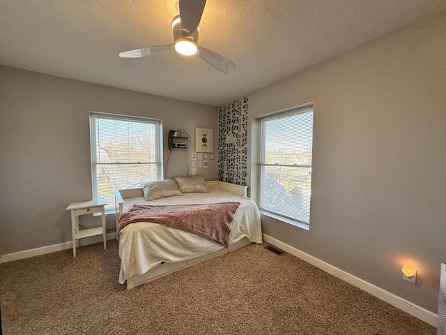 carpeted bedroom featuring ceiling fan and a textured ceiling