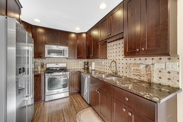 kitchen featuring decorative backsplash, dark stone counters, sink, light hardwood / wood-style floors, and stainless steel appliances