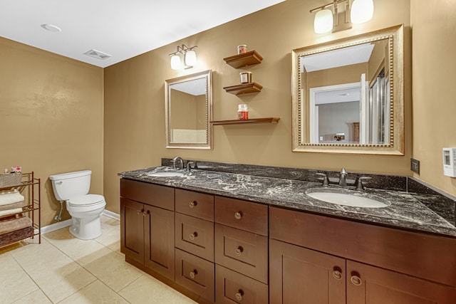 bathroom with toilet, vanity, and tile patterned flooring