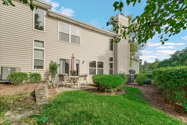 rear view of property featuring a patio, central AC, and a lawn