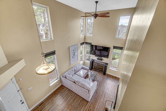 living room with wood-type flooring, a high ceiling, and ceiling fan