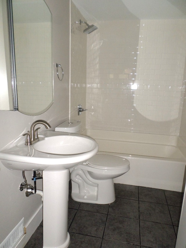 bathroom with toilet, tile patterned flooring, and tiled shower / bath