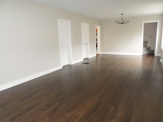 spare room featuring dark hardwood / wood-style flooring and a chandelier