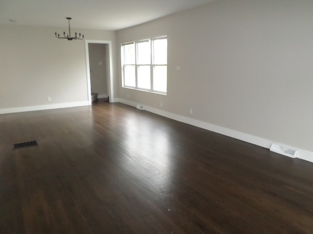 empty room with an inviting chandelier and dark hardwood / wood-style floors