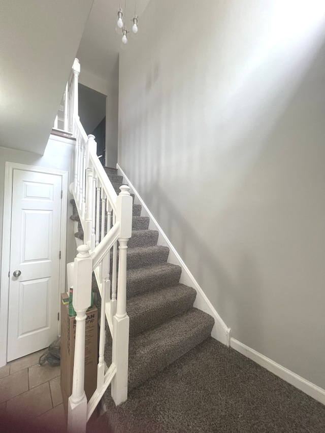 stairway with an inviting chandelier and carpet