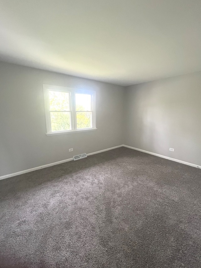 unfurnished room featuring dark carpet