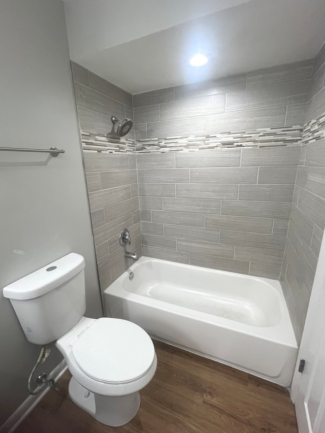 bathroom with toilet, wood-type flooring, and tiled shower / bath