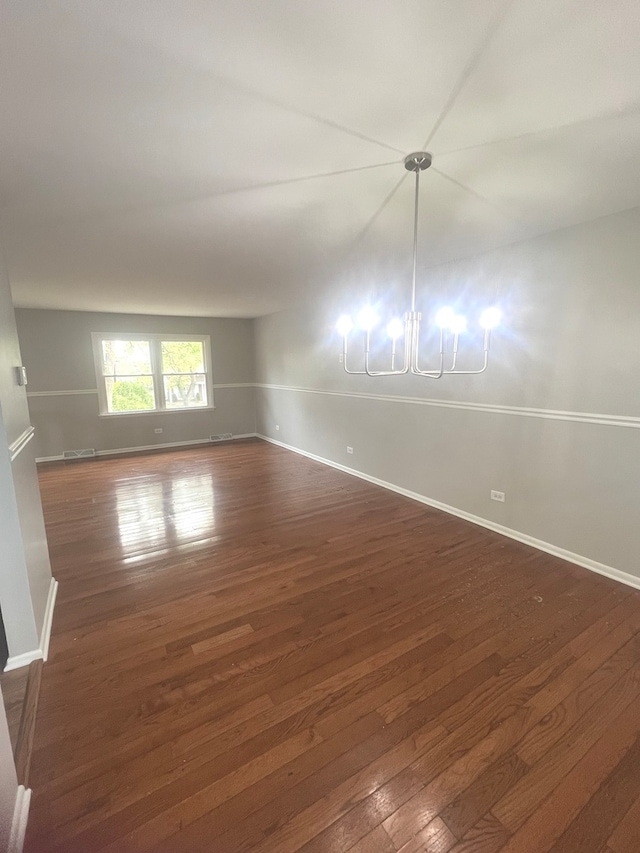 unfurnished room featuring a notable chandelier and dark hardwood / wood-style flooring