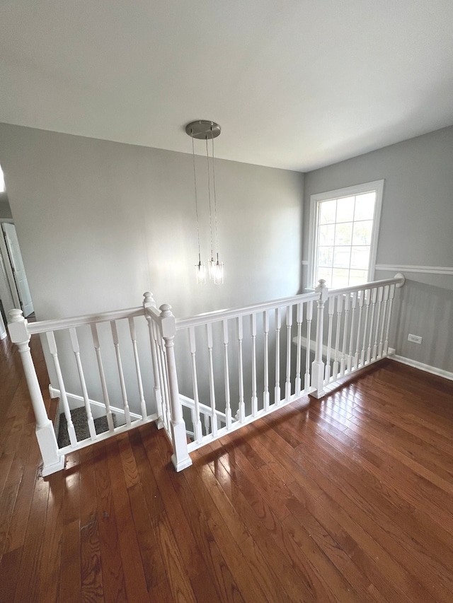 staircase with wood-type flooring and a chandelier