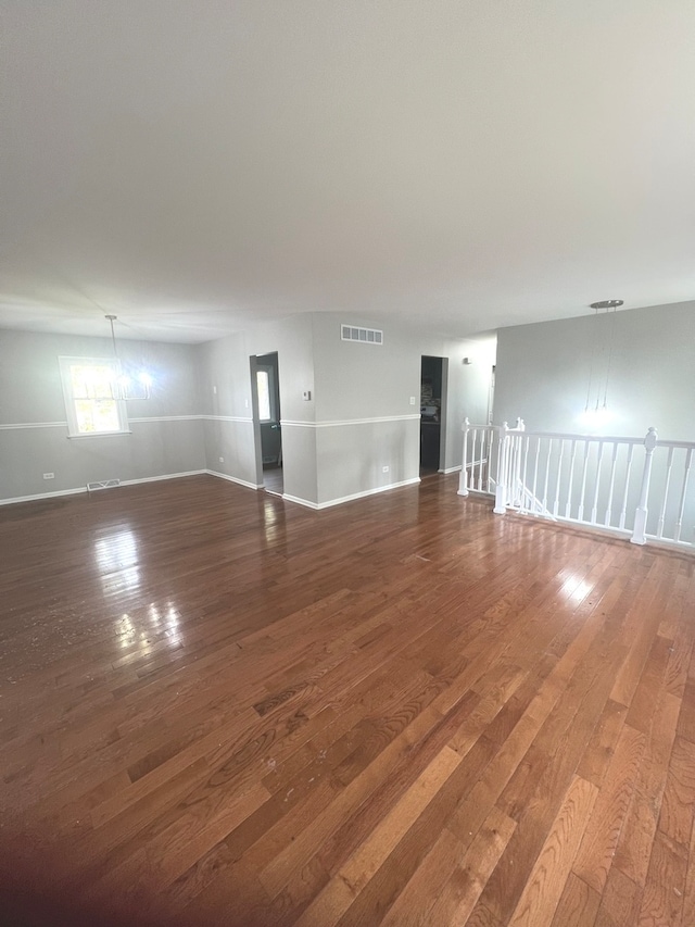 empty room featuring a notable chandelier and dark hardwood / wood-style flooring